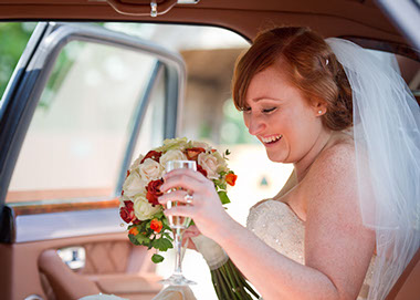 Image of Bride in the bridal car with bouquet and champagne taken by Natasha Hirst.