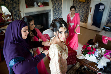 Bride getting changed on her wedding day in the Bride's bedroom of Hagley Hall. Image by Natasha Hirst.